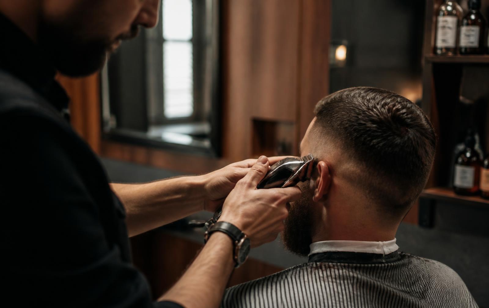 A barber finishing a fade in a warm, modern barbershop